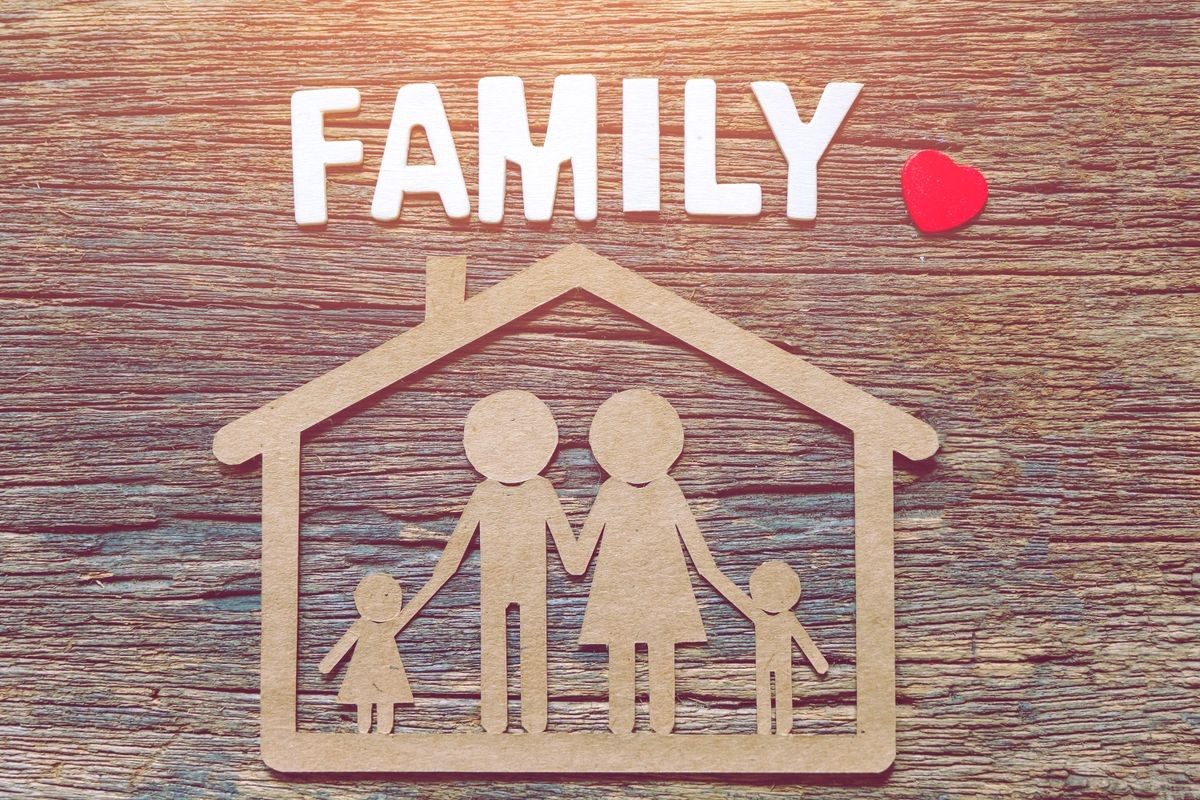 Paper cut of a family and house on wood table with wooden letter blocks writing word FAMILY . Save and investment money for prepare in the future - Saving money concept.