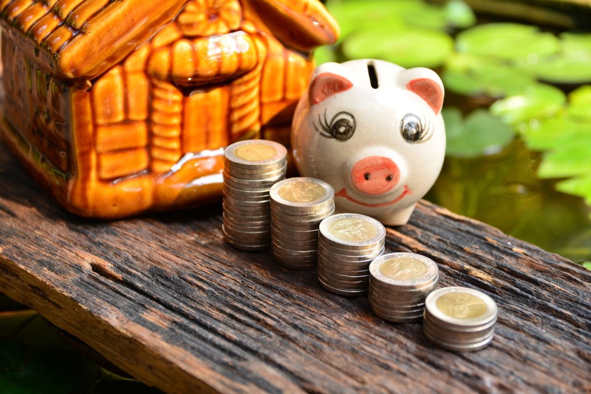 Stack coins beside piggy bank and front of mini house for financial and tax season.